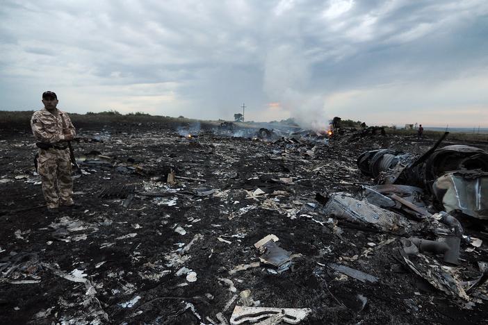 A man wearing military fatigues stands next to the wreckage of Malaysia Airlines MH17 carrying 298 passengers and crew, that crashed in eastern Ukraine six years ago.