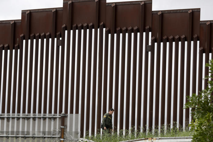 A Border Patrol agent walks along a border wall separating Tijuana, Mexico, from San Diego, in March 2020.
