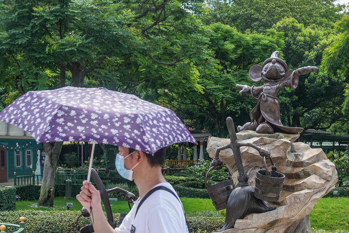 A visitor wearing a protective mask walks past a statue of Mickey Mouse at the Hong Kong Disneyland Resort on June 18, the day it initially reopened. The amusement park will close again on Wednesday.