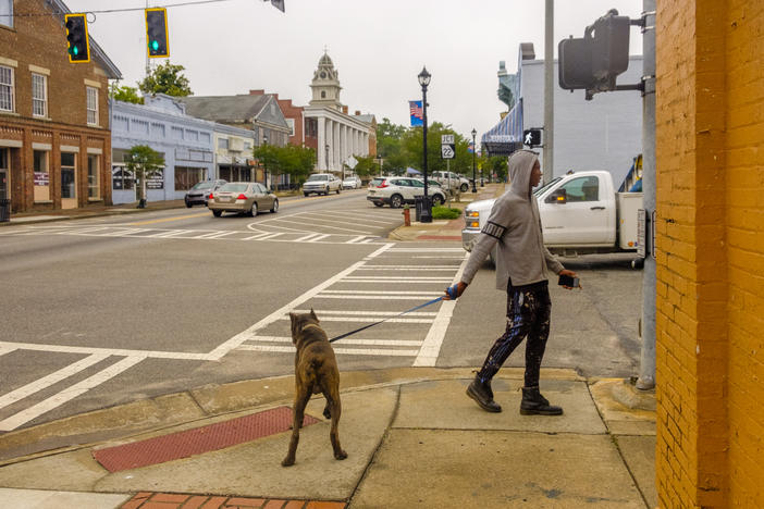 Amariel Yehudah walks his dog Draco in downtown Sparta, the Hancock County seat. Yehudah was surprised to learn his town was a coronavirus hotspot.