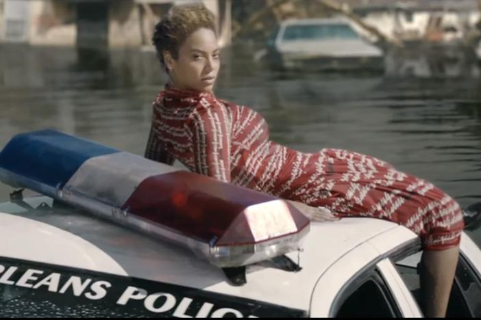 A scene from the Formation music video that shows BeyoncÃ© on a New Orleans police car in the aftermath of Hurricane Katrina.