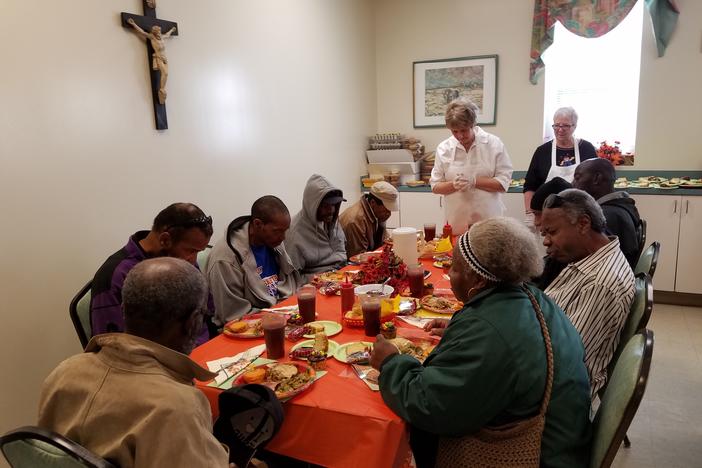 Diners pray with a volunteer before their Thanksgiving meal at Savannah's Social Apostolate.