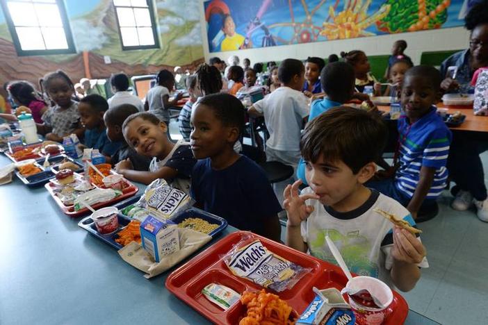 Kindergartner Landon Hall (right) licks his fingers as he finishes off his peanut butter and jelly sandwich at Alexander II Magnet School where students began their lunch at 10:30 in the morning. 