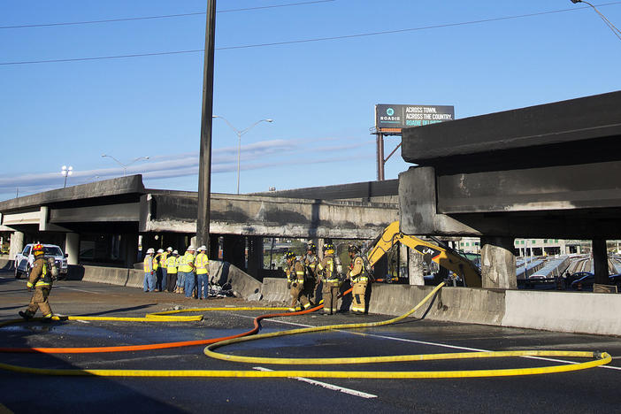 A portion of Interstate 85 that collapsed in March will reopen Monday, Georgia officials say. Here, construction workers and firefighters survey a section of the overpass that collapsed from a large fire in Atlanta.