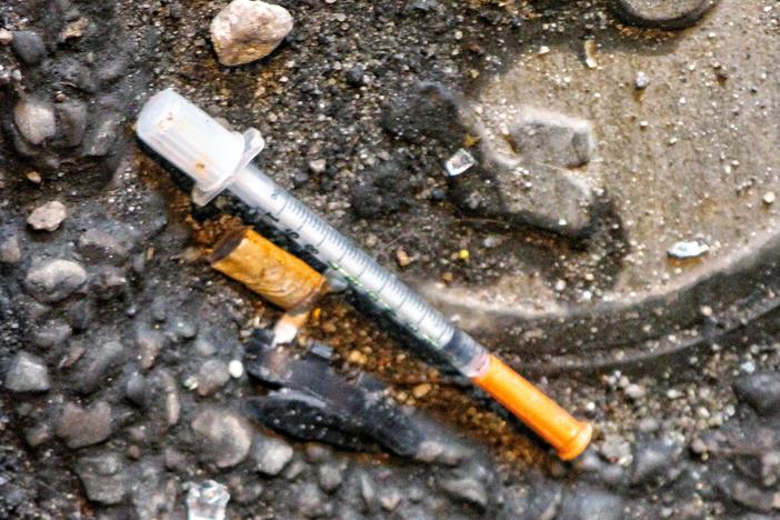 A syringe discarded in a street.