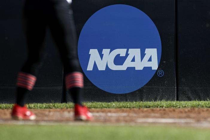 In this April 19, 2019 photo an athlete stands near a NCAA logo in Beaumont, Texas. The NCAA voted to allow college athletes to earn money without violating amateurism rules.
