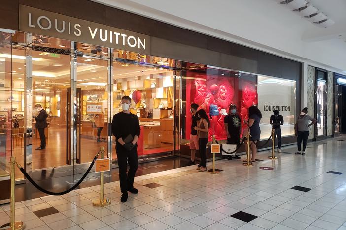 Shoppers wait to get inside the Louis Vuitton store at Lenox Square. Simon-owned malls across the state reopened on Monday. 