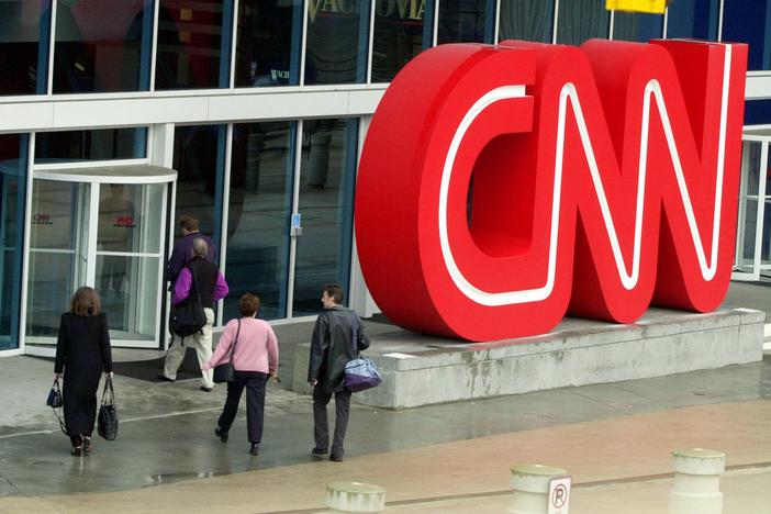 Pedestrians enter CNN Center, the headquarters for CNN, in downtown Atlanta, Wednesday, Jan. 17, 2001.