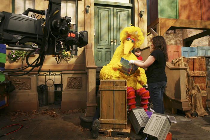 Michelle Hickey, a muppet wrangler, helps Big Bird hold a book during a rehearsal of "Sesame Street" in New York.