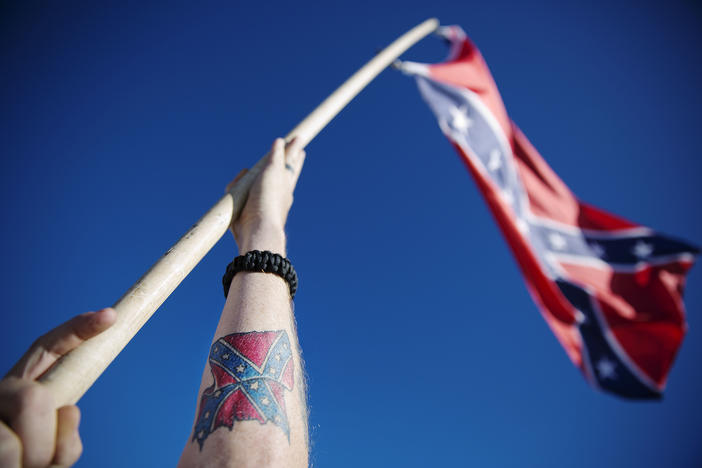 A tattoo of a Confederate flag decorates the arm of William Phillips, of Griffin, Georgia, as he waves a Confederate flag after hiking to the top of Stone Mountain during a rally with flag supporters Saturday, Nov. 14, 2015, in Stone Mountain.