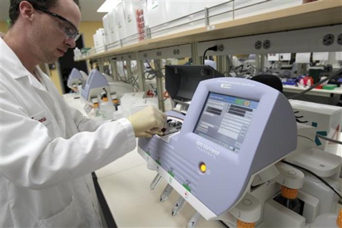 Scientist Tommie Lincecum works with a machine that reads DNA and is being used to help decode genomes in the outbreaks of E. coli.