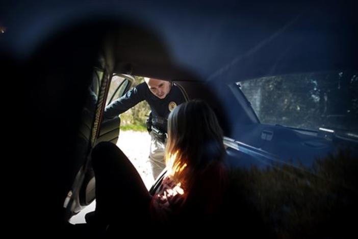 Homeless Liaison Officer Tom Gentner talks to one of the homeless residents he keeps track of after she was arrested for prostitution on the west side of Savannah in February 2014.