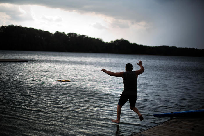 Radko Jonas jumps into the water to retrieve a life vest that blew away as rain clouds approach at Lake Lanier Tuesday, July 19, 2016.