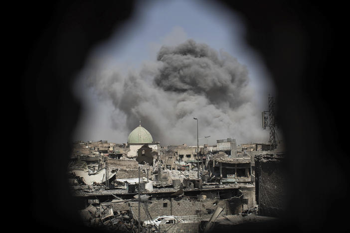 A bomb explodes behind the al-Nuri mosque complex, as seen through a hole in the wall of a house, as Iraqi Special Forces move toward Islamic State militant positions in the Old City of Mosul, Iraq, Thursday, June 29, 2017. (AP Photo/Felipe Dana)