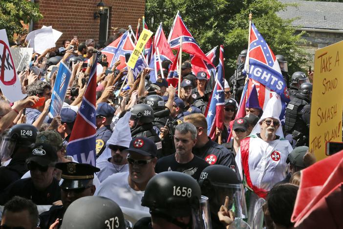 Members of the KKK are escorted by police past a large group of protesters during a KKK rally Saturday, July 8, 2017, in Charlottesville, Va.