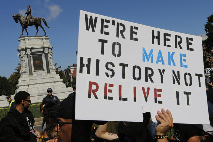 Protesters hold signs in front of the statue of Confederate General Robert E. Lee on Monument Avenue in Richmond, Va., Saturday, Sept. 16, 2017. The group of Confederate demonstrators were escorted out by police after a 50 minute protest.