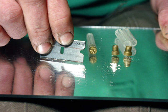 A razor blade is used to divide the contents of a five-dollar vile of crack, a smokable, purified form of cocaine, at a crack house in the South Bronx section of New York in 1989. 