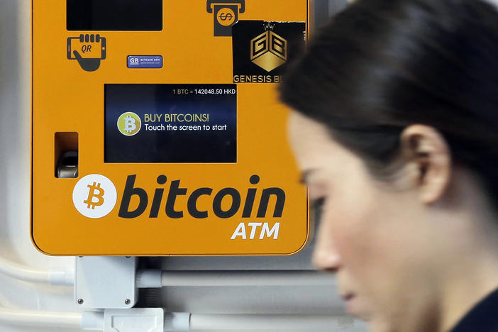 In this Dec. 21, 2017 file photo, a woman walks past the Bitcoin ATM in Hong Kong. 