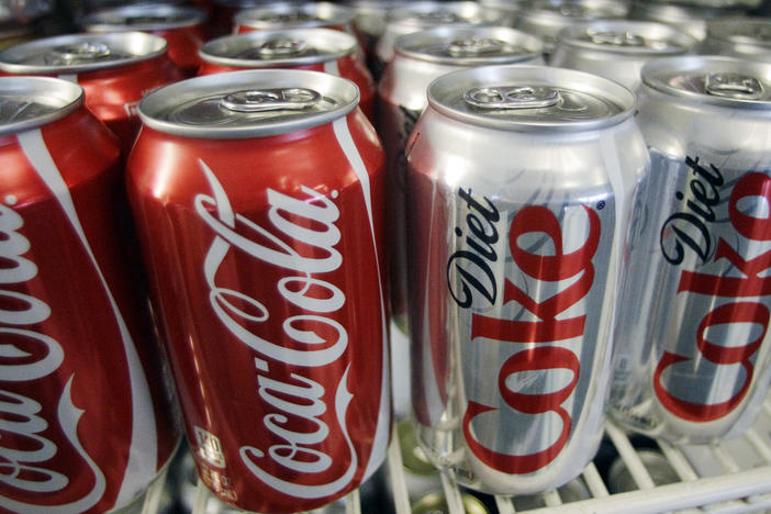 In this March 17, 2011, file photo, cans of Coca-Cola and Diet Coke sit in a cooler in Anne's Deli in Portland, Ore. The Coca-Cola Co. plans to help collect and recycle a bottle or can for every one that it sells by 2030.