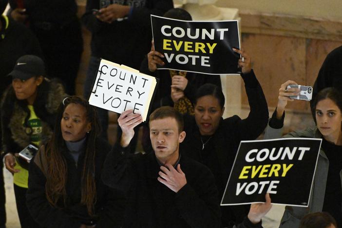 People hold signs as they protest the election in the rotunda of the state capitol building Tuesday, Nov. 13, 2018, in Atlanta.