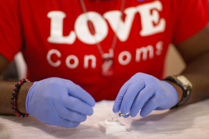 In this June 27, 2013, file photo, Reggie Batiste, program manager with AIDS Healthcare Foundation, administers a free HIV test as part of National HIV Testing Day in Atlanta.