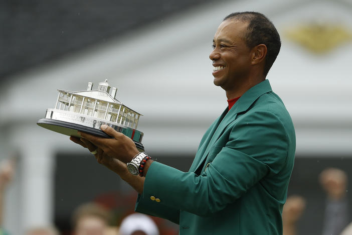Tiger Woods wears his green jacket holding the winning trophy after the final round for the Masters golf tournament Sunday, April 14, 2019, in Augusta, Ga.