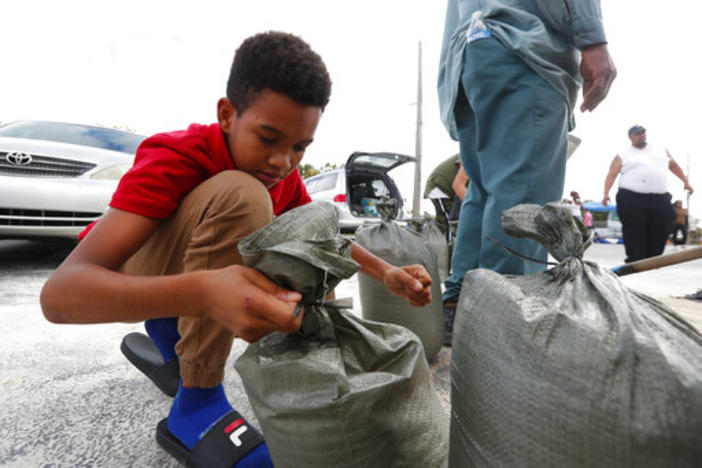Isaiah Elie, 11, helps tie sandbags as his family fills them in preparation for Hurricane Dorian, Friday, Aug. 30, 2019, in Hallandale Beach, Florida.