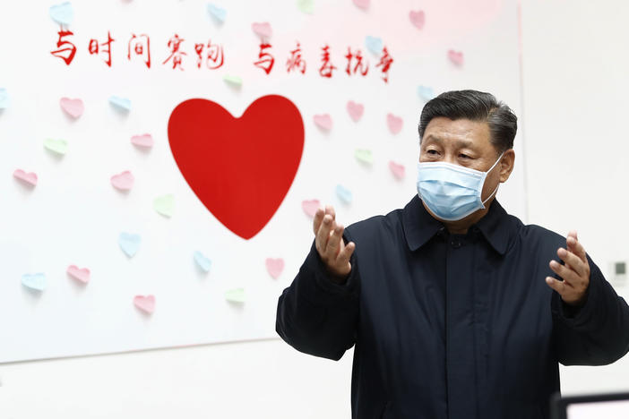 Chinese President Xi Jinping gestures near a heart shape sign and the slogan "Race against time, Fight the Virus" during an inspection of the center for disease control and prevention in Beijing.