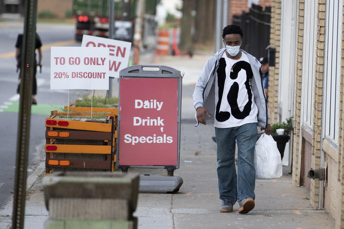 A man leaves a restaurant with a takeout order Thursday, March 19, 2020 in Atlanta. 