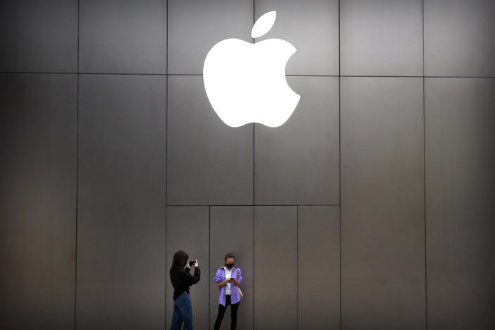 Women wear face masks to protect against the spread of the new coronavirus as they stand near an Apple store in Beijing, Friday, April 24, 2020.