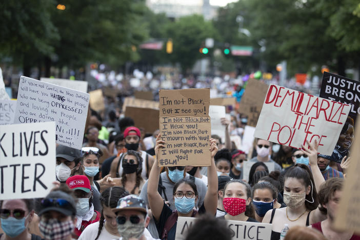 People carry signs as they march Monday, June 1, 2020, in Atlanta during a demonstration over the death of George Floyd.
