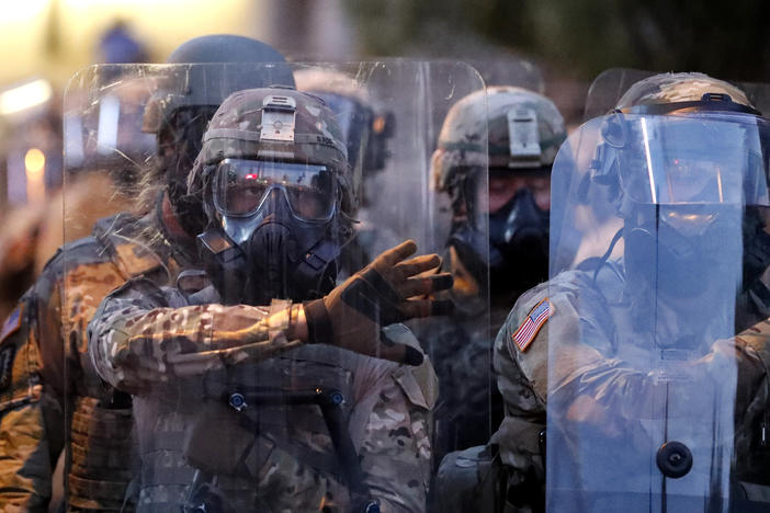 Georgia National Guard troops prepare to enforce a 9:00 pm curfew as demonstrators chant, Tuesday, June 2, 2020, in Atlanta. 