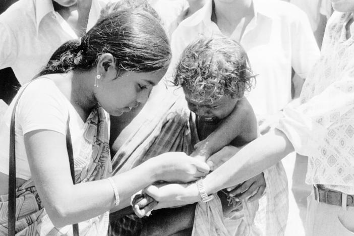 Two members of an Indian medical team get together to vaccinate a small child against smallpox at Hakegora village in India's Bihar state, June 23, 1974.