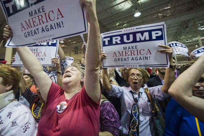 Supporters Kathleen Hastings, left, and Elizabeth Musngi, right, cheers Republican presidential candidate Donald Trump as he speaks during a campaign rally held at the North Atlanta Trade Center, Saturday, Oct., 10, 2015, in Norcross, Ga.
