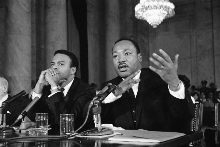 Dr. Martin Luther King, Jr., president of Southern Christian Leadership Conference, testifies, Dec. 15, 1966 before a Senate Government Operations Subcommittee studying urban problems and poverty. Rev. Andrew Young is left.
