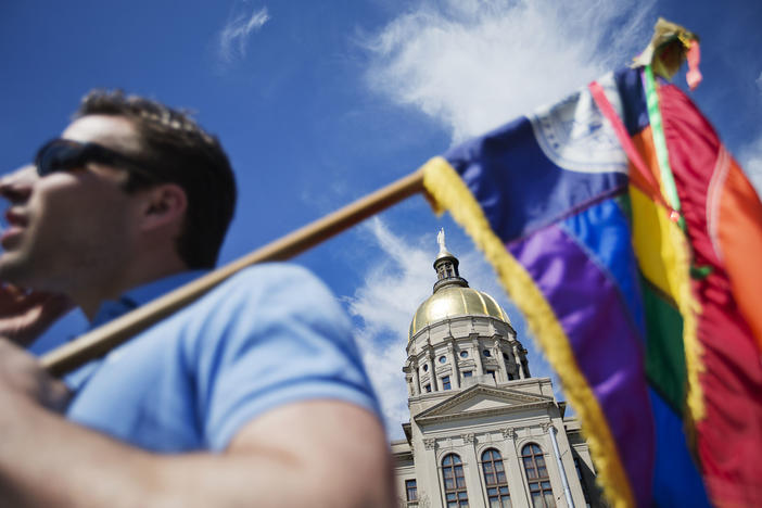 In this March 17, 2015, file photo, the dome of the Capitol stands in the background as Stephen Saras, of Atlanta, holds a rainbow-colored flag during a rally against a contentious "religious freedom" bill in Atlanta. 