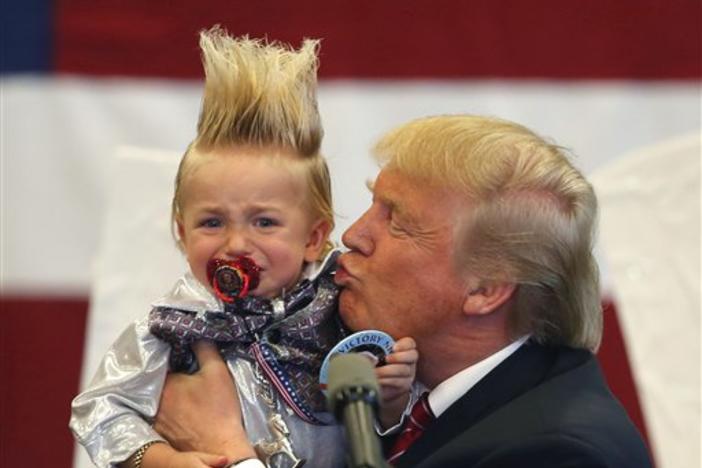 Republican presidential candidate Donald Trump holds up a child he pulled from the crowd as he arrives to speak at a campaign rally in New Orleans, Friday, March 4, 2016.