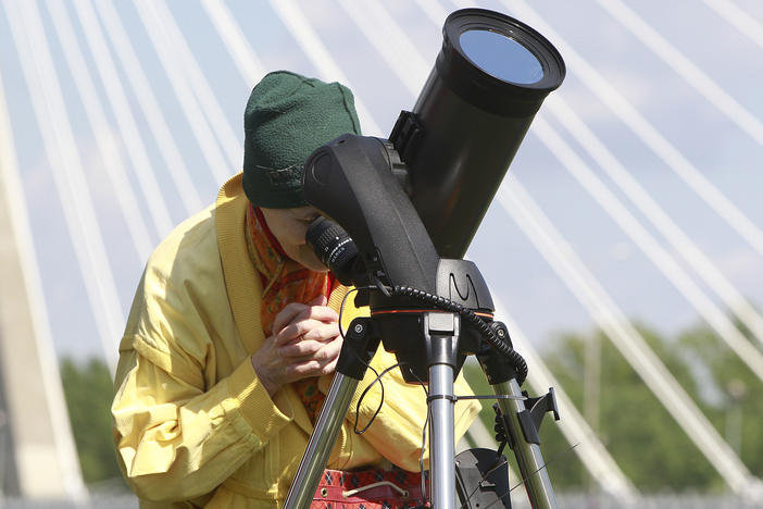 A woman watches through specially secured telescope as planet Mercury passes against the Earth and the Sun in a rare astronomical occurrence before the Copernicus Science Center in Warsaw, Poland, Monday, May 9, 2016.