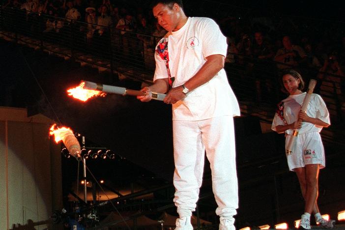 American swimmer Janet Evans looks on as Muhammad Ali lights the Olympic flame during the 1996 Summer Olympic Games opening ceremony in Atlanta Friday, July 19, 1996.