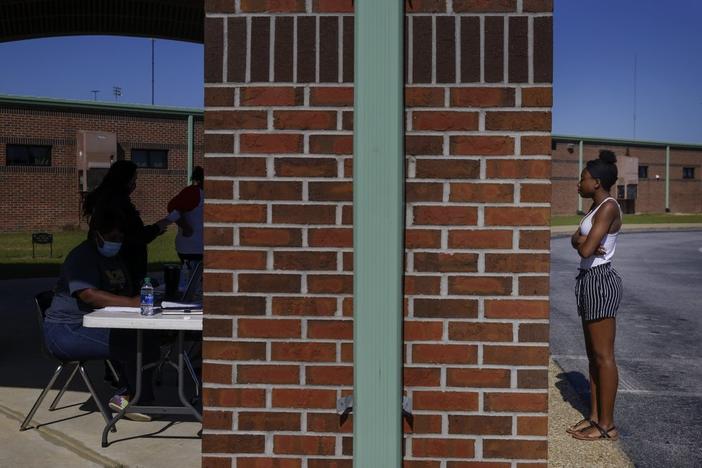 In this Thursday, May 7, 2020 photo, Azandria Torbert, stands in line for graduation information at Chattahoochee County High School after the school district called an early end to the school year, in Cusseta, Ga. 