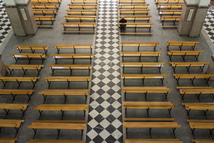 A Catholic priest sits on an empty bench due to social distancing guidelines during the coronavirus outbreak inside the Jesus de Medinaceli church on Palm Sunday in Madrid, Spain, Sunday, April 5, 2020.