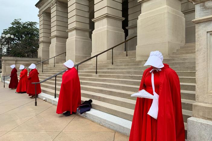Women dressed in 'Handmaid's Tale' costumes stand outside the Georgia State Capitol in protest to 'Heartbeat Bill.'