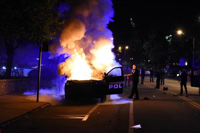 A Georgia Tech police officer attempts to extinguish a fire inside a patrol vehicle on campus Monday, September 18.