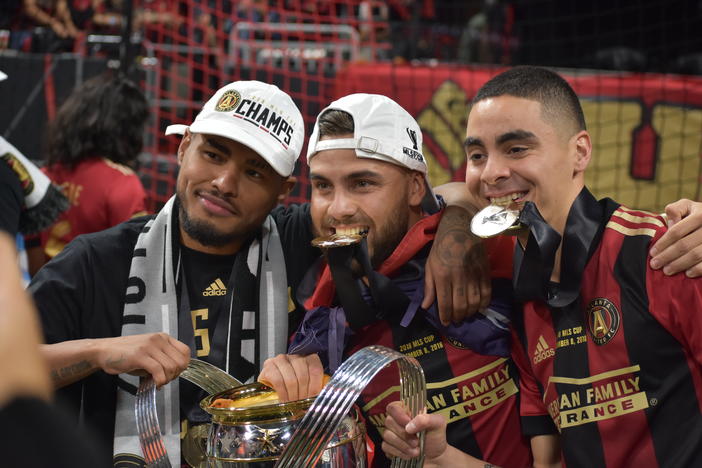 Almiron (right) poses with teammates Josef Martinez (left) and Tito Villalba (center) after Atlanta United's MLS Cup win in December