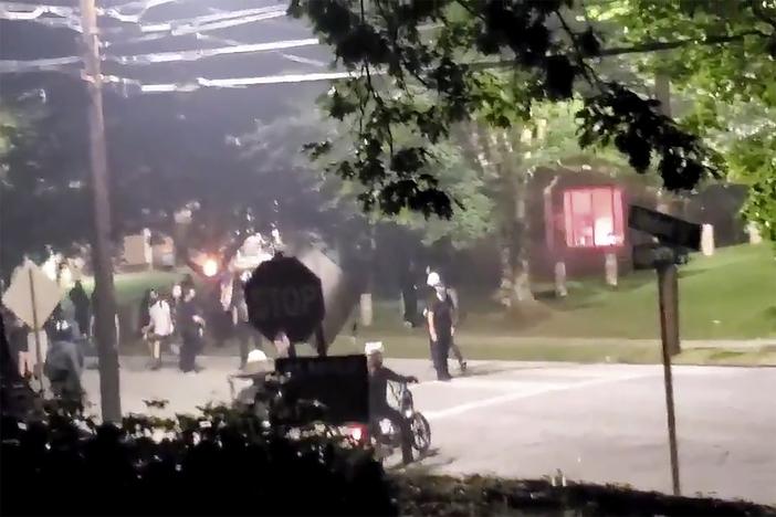 The building, seen right in the background, that houses Georgia State Patrol headquarters is vandalized in Atlanta, Sunday, July 5, 2020. Video showed protesters appearing to set off at least one firework inside the building.