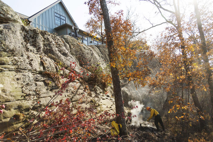 A firefighter rakes a patch of smoldering woods below a home on Lookout Mountain during a wildfire in 2016. A new U.S. Forest Service plan would thin over 157,000 acres of national forest in Georgia, in part to mitigate wildfire risk. 