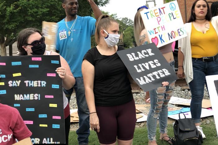 A group gathers in downtown Woodstock with signs that say "Black Lives Matter" as they protest racial injustice and police brutality. 