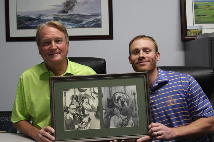 Kenny Stanton (left) and Zack Stanton hold a photo of Kenny as a baby in the horn of Marietta Daily Journal publisher Otis J. Brumby. On the right of the framed photo, Kenny holds a horn with son Zack inside.