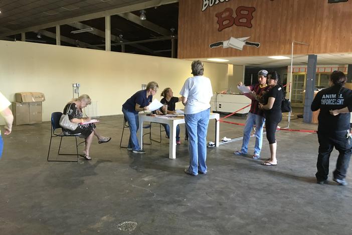 Cheryl Cardinal (seated on left) from Key Largo, Florida fills out paperwork as she drops her cat off at the Macon shelter designated for pets.