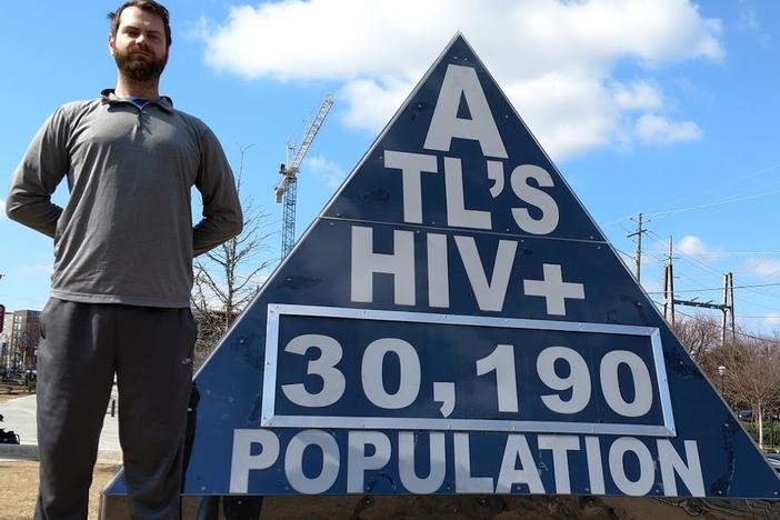 In this Feb. 19, 2017  photo, freelance journalist Matt Terrell stands next to a marker he designed that shows Atlanta's HIV infection rate, which is updated once a week. It is on display outside the Center for Civil and Human Rights in Atlanta.